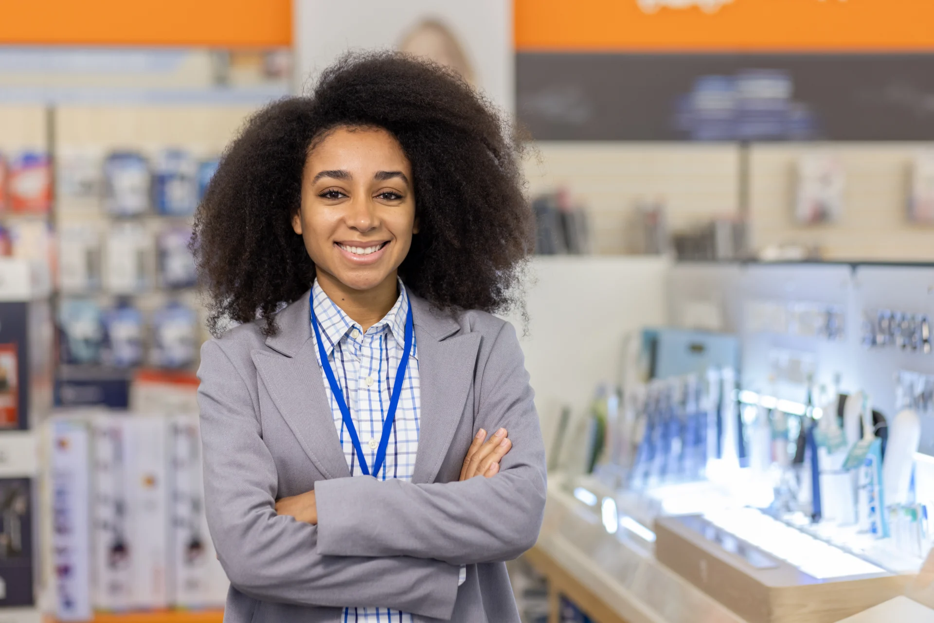 Confident female retail employee smiling inside electronics store