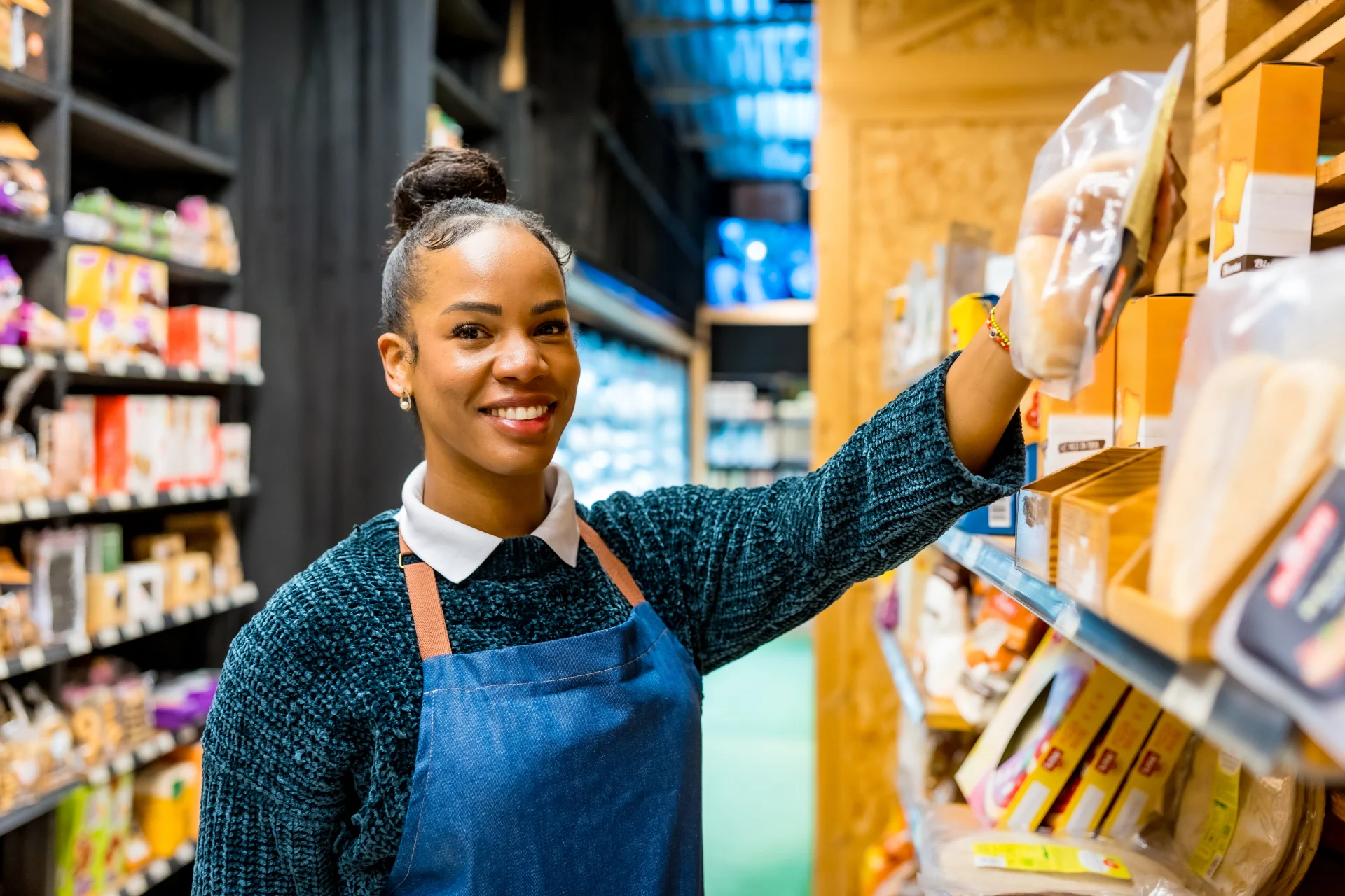 Smiling saleswoman arranging products on shelves in organic supermarket